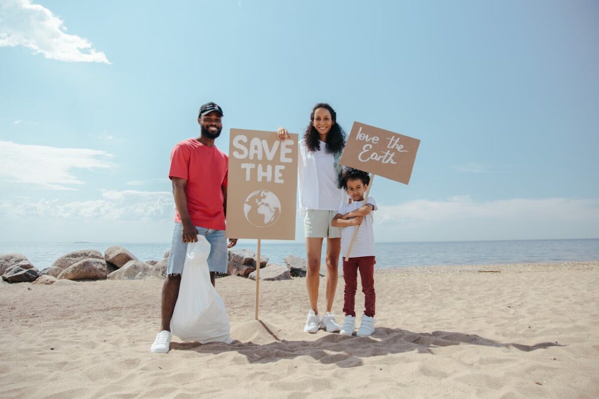 Family on the beach participating in a cleanup, holding signs to promote saving the planet and showing environmental consciousness.